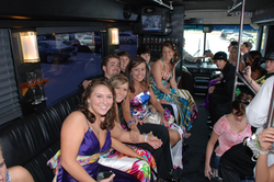 A group of excited prom-goers celebrating in a vibrant party bus in Plano