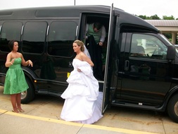 A beaming bride gracefully stepping out of a beautifully decorated bus in Plano